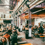 Rows of tables with benches, with people dining, at The Steamworks.