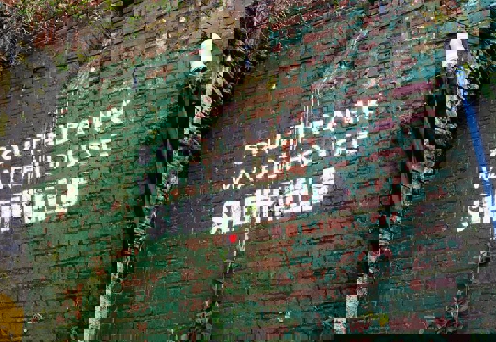 Southbank Warehouse stencilled on to a red brick wall that is partially covered in peeling green paint.