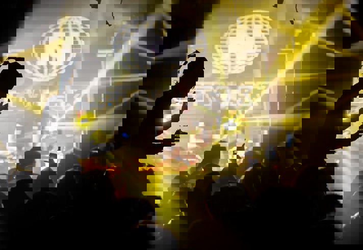 A nightclub full of people dancing, lit by yellow lighting.