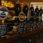 A row of beer taps on a traditional pub bar.