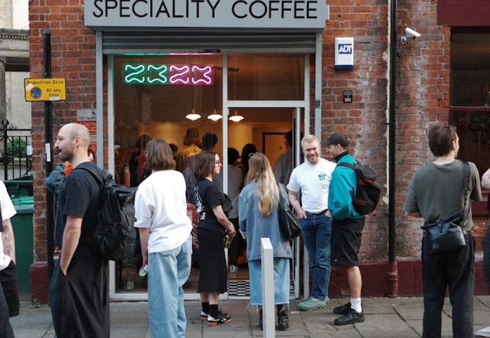 exterior of 2323 coffee shop with people stood on the cobbled street outside 