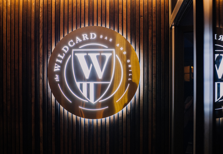 The Wildcard Bar & Grill's logo, lit up, on a wall.