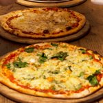 Pizzas fresh out the oven about to be cut up into slices.