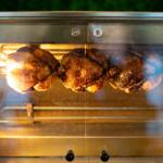 Three chickens in a rotisserie oven at Chop Shop Bar & Grill.