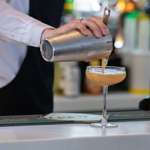 A cocktail being poured into a Champagne glass. 