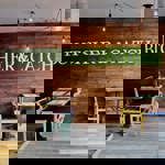 Restaurant tables next to a naked brick wall with a green sign that reads 'Butcher & Catch'.