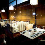 The interior of Tsuki, with a row of 4 tables in booths with subdued lighting.