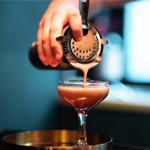 A cocktails being poured from a shaker.