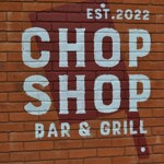 The Chop Shop Bar & Grill logo painted on a red brick wall.